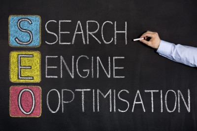 Hand writing SEO acronym on chalkboard with Search Engine Optimisation spelled out