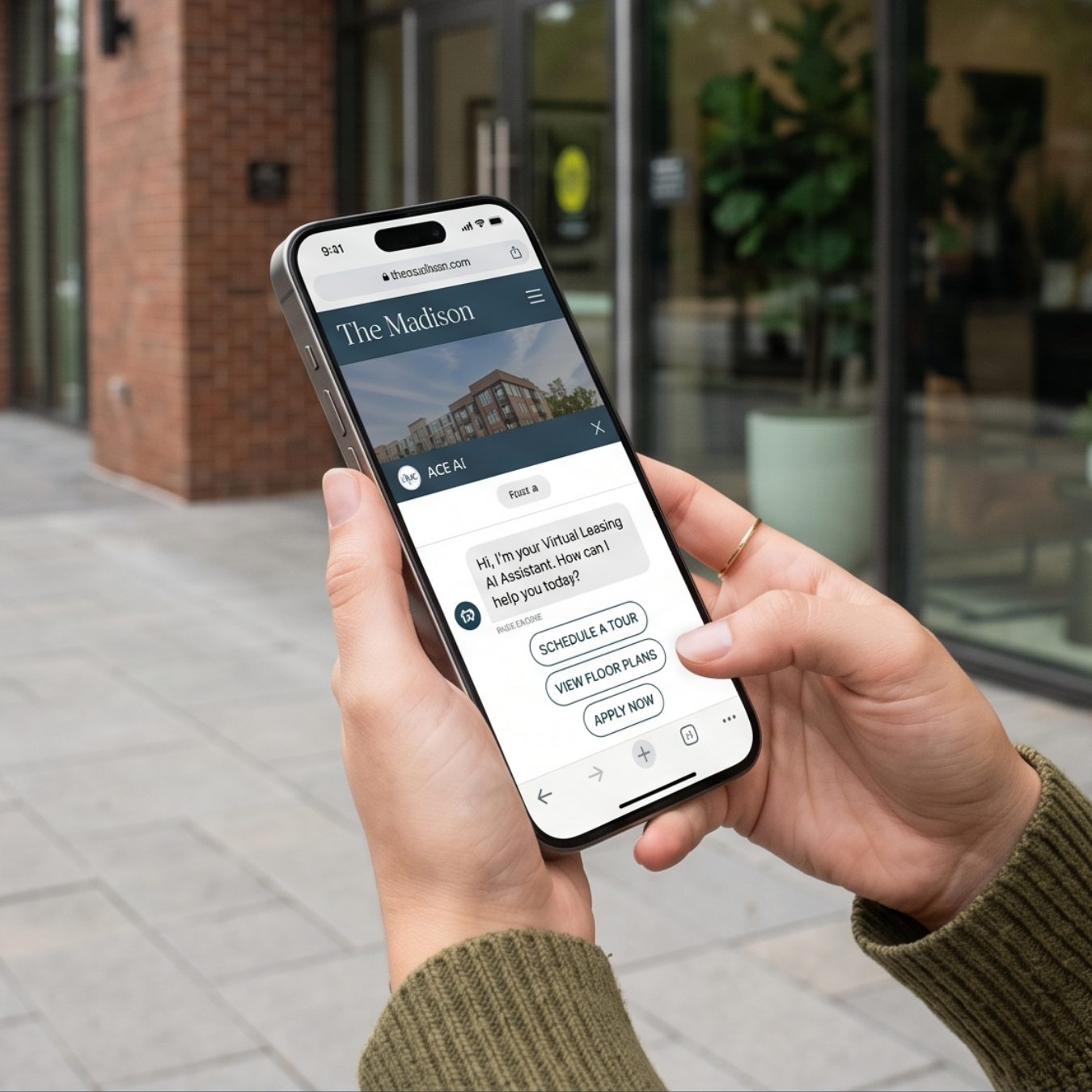 Hand holding a smartphone showing The Madison website with an AI leasing assistant chat offering tour scheduling and floor plans