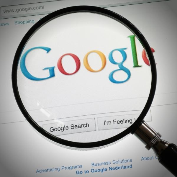 Magnifying glass zooms in on the Google logo above the search bar on a webpage