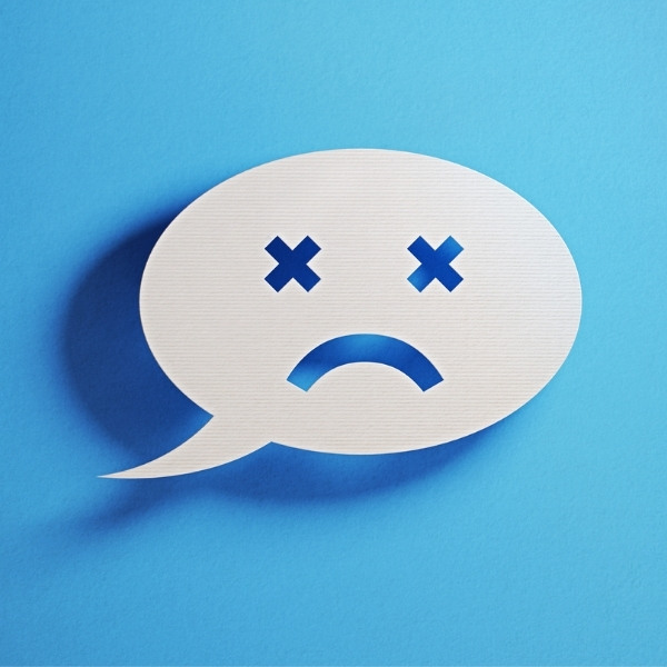 White speech bubble with X eyes and a frown, symbolizing a negative review on a blue background